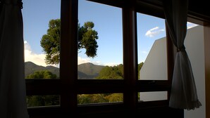 Une pièce dotée d’une grande fenêtre donnant sur un paysage de montagnes et d’arbres.