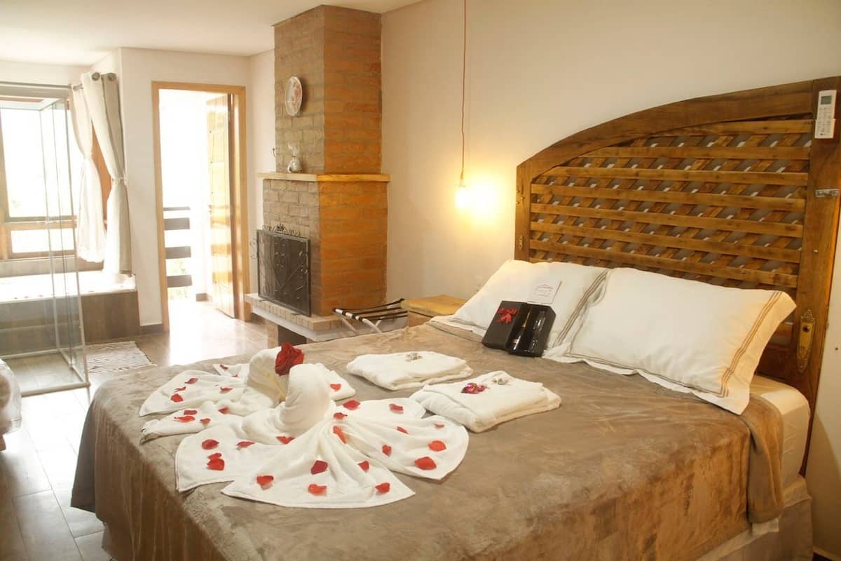 A hotel room with a large bed, a fireplace, and a wooden headboard.