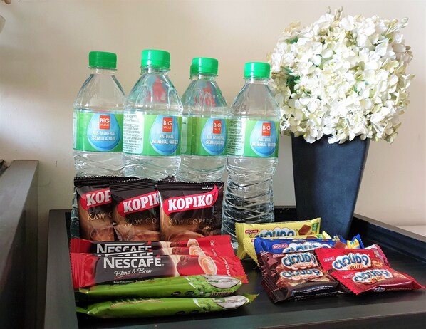 Bottled water, Kopi coffee, Nescafe, and Cloudy Plus snacks on a table. - Zenith Suite Residence (Johor Bahru)
