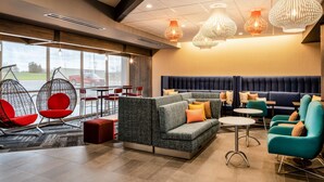 A modern lounge area with seating arrangements, including sofas and chairs, and a large window offering a view of the outside.