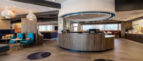 A hotel lobby with a reception desk, seating area, and a view of the outside.