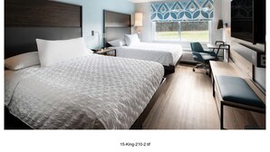 A hotel room with two beds, a desk, a chair, a TV, and a window with a view of the outdoors.