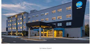 A modern hotel building with a clear entrance, multiple floors, and a prominent logo on the side.