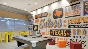 Una mesa de billar en una habitación con un mural que muestra varios nombres de ciudades y logotipos.
