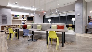 Un área de estar moderna con un sofá, sillas, una mesa y un televisor.