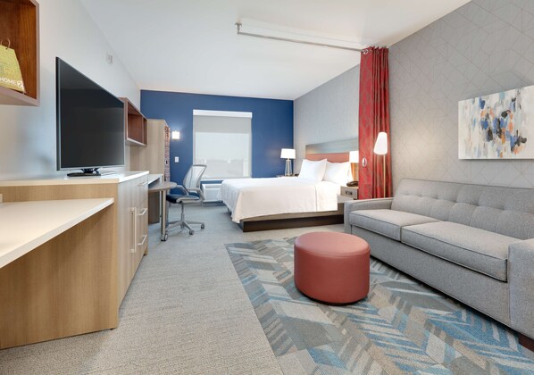 Una habitación de hotel con cama, sofá, televisor, escritorio y silla.