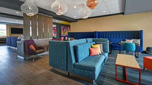 Un hall d’entrée moderne avec un canapé bleu, un fauteuil violet et une table rouge.