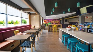 Un restaurant moderne avec des tables hautes, des bancs et des tabourets colorés.