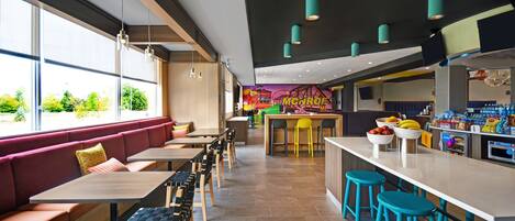 Un ristorante moderno con tavoli alti, panche e sgabelli colorati.