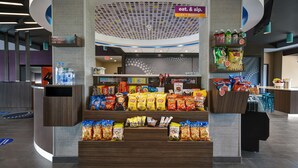 Un présentoir de collations dans un espace de vente moderne, proposant une variété de chips et de boissons en bouteille.