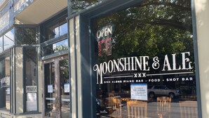 Ein Schaufenster mit einem Schild, auf dem „Moonshine & Ale“ und „Neueröffnung“ steht.