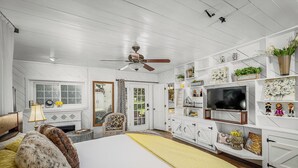 Ein Schlafzimmer mit einem Bett, einem Deckenventilator, einem Fernseher und einem Kamin.