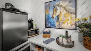 Eine Küche mit einem Edelstahlkühlschrank, einer Mikrowelle, einem Spülbecken und einem Gemälde eines Pferdes.