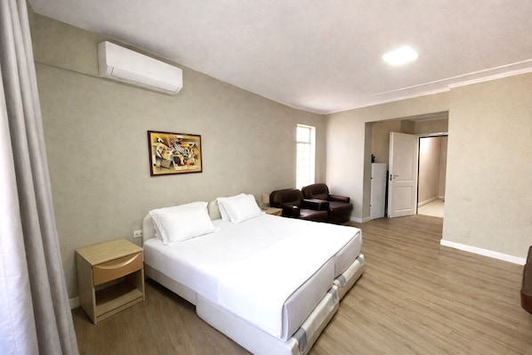 Ein Hotelzimmer mit einem Bett, einem Schreibtisch, einem Stuhl, einem Bild an der Wand und einer Klimaanlage.