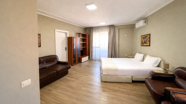 Ein Hotelzimmer mit Bett, Sofa, Kleiderschrank und Schreibtisch.