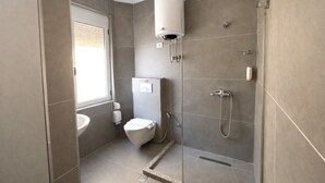 Ein modernes Badezimmer mit Toilette, Waschbecken, Dusche und Warmwasserbereiter.