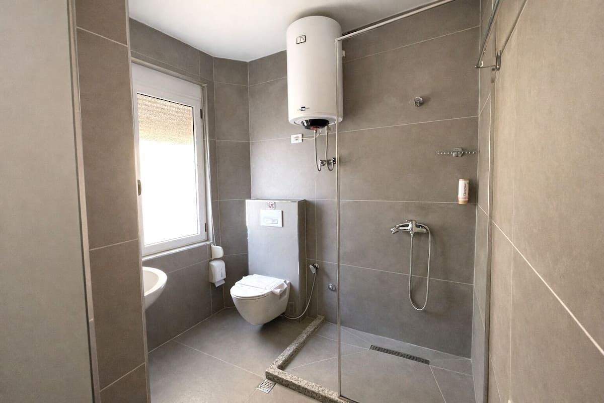 Chuveiro, secador de cabelo, chinelos, toalhas de banho