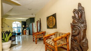 A lobby with bamboo chairs, a large wall carving, and a painting. - Mirador Hotel (Corozal)