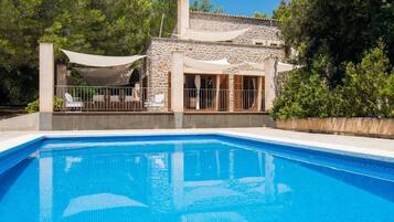 A swimming pool with a stone house in the background.
