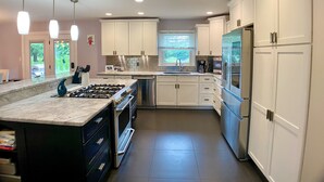 A modern kitchen with white cabinets, stainless steel appliances, and a marble countertop. - PRIVATE heated pool & hot tub, dogs ok, near Keeneland (Lexington)