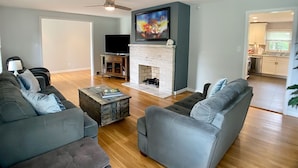 A living room with a fireplace, grey sofas, a coffee table, and a television. - PRIVATE heated pool & hot tub, dogs ok, near Keeneland (Lexington)