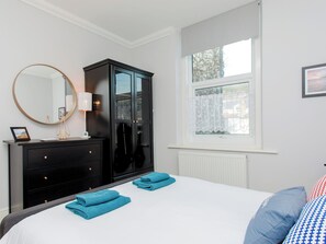 A bedroom with a bed, a dresser, a mirror, a window with a view, and a radiator.