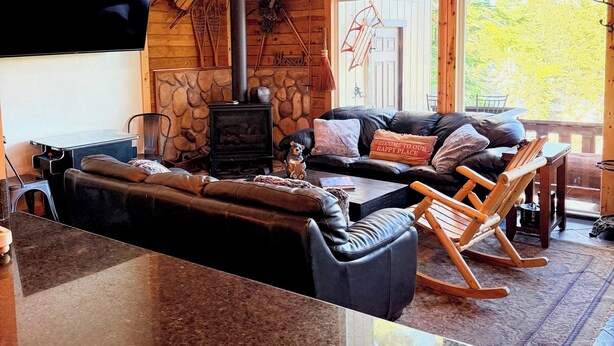 A cozy living area with a fireplace, leather sofa, wooden rocking chair, and a stone wall. - HEAVENLY MOUNTAIN RETREAT (Stateline)