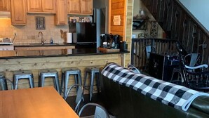 A cozy kitchen with wooden cabinets, a black refrigerator, and a bar area with stools. - HEAVENLY MOUNTAIN RETREAT (Stateline)