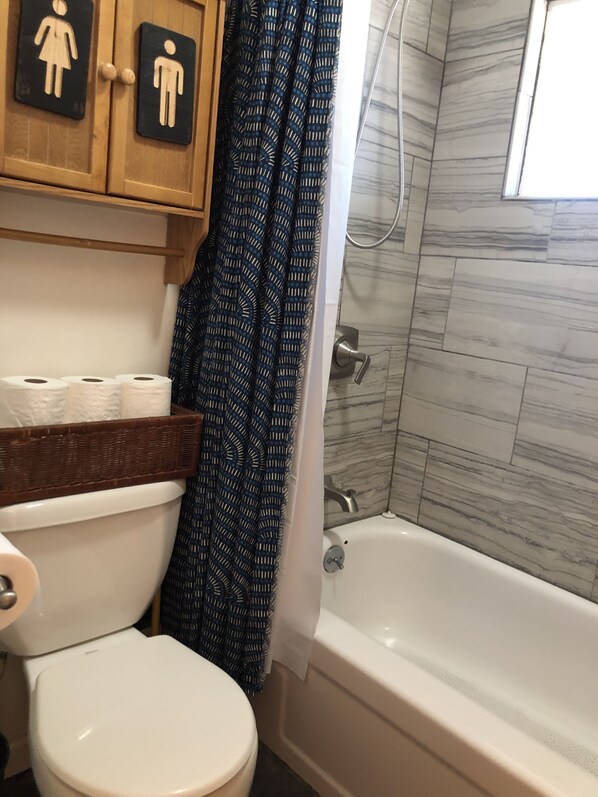A bathroom with a toilet, a shower, and a bathtub. There are toilet paper rolls and a basket on the counter. - HEAVENLY MOUNTAIN RETREAT (Stateline)