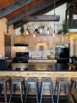 A kitchen with wooden cabinets, a black refrigerator, and a central island with stools.