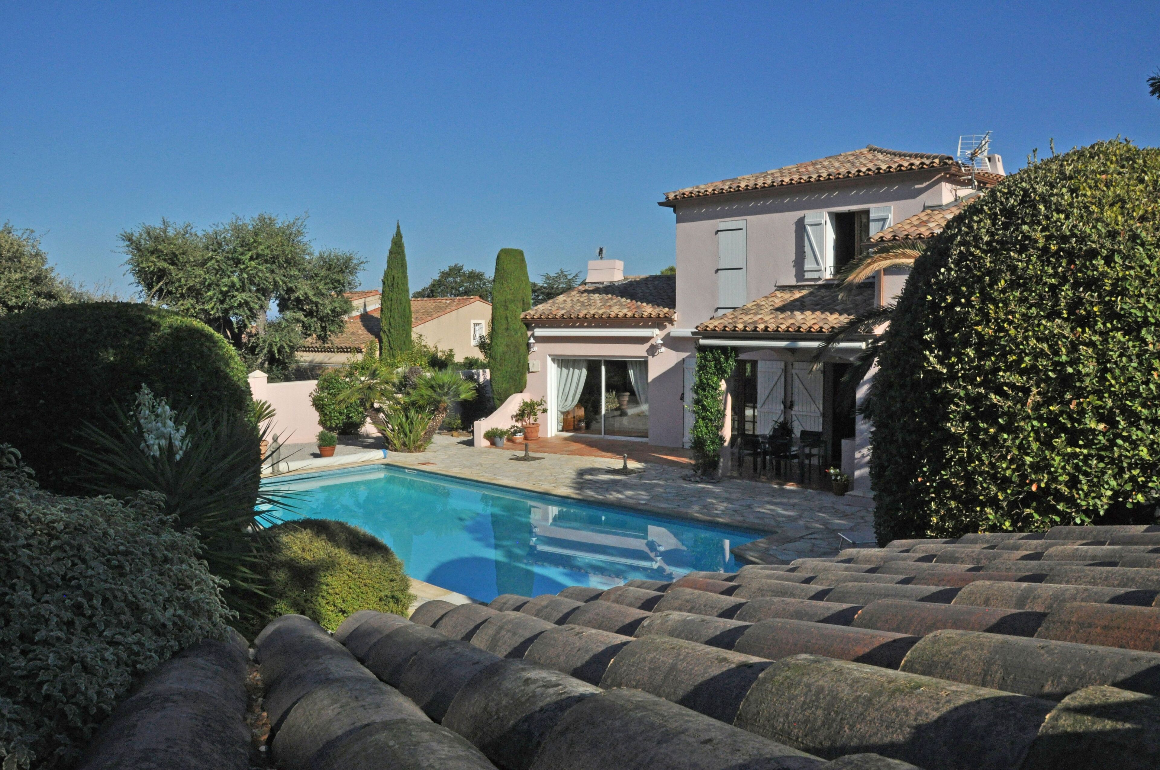 A swimming pool surrounded by stone steps and greenery, with a building in the background.