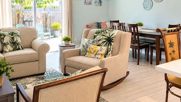 A living room with a sofa, chairs, a dining table, and a view of the outdoors.