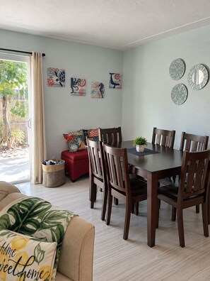A dining area with a table and chairs, a red sofa, and wall art.
