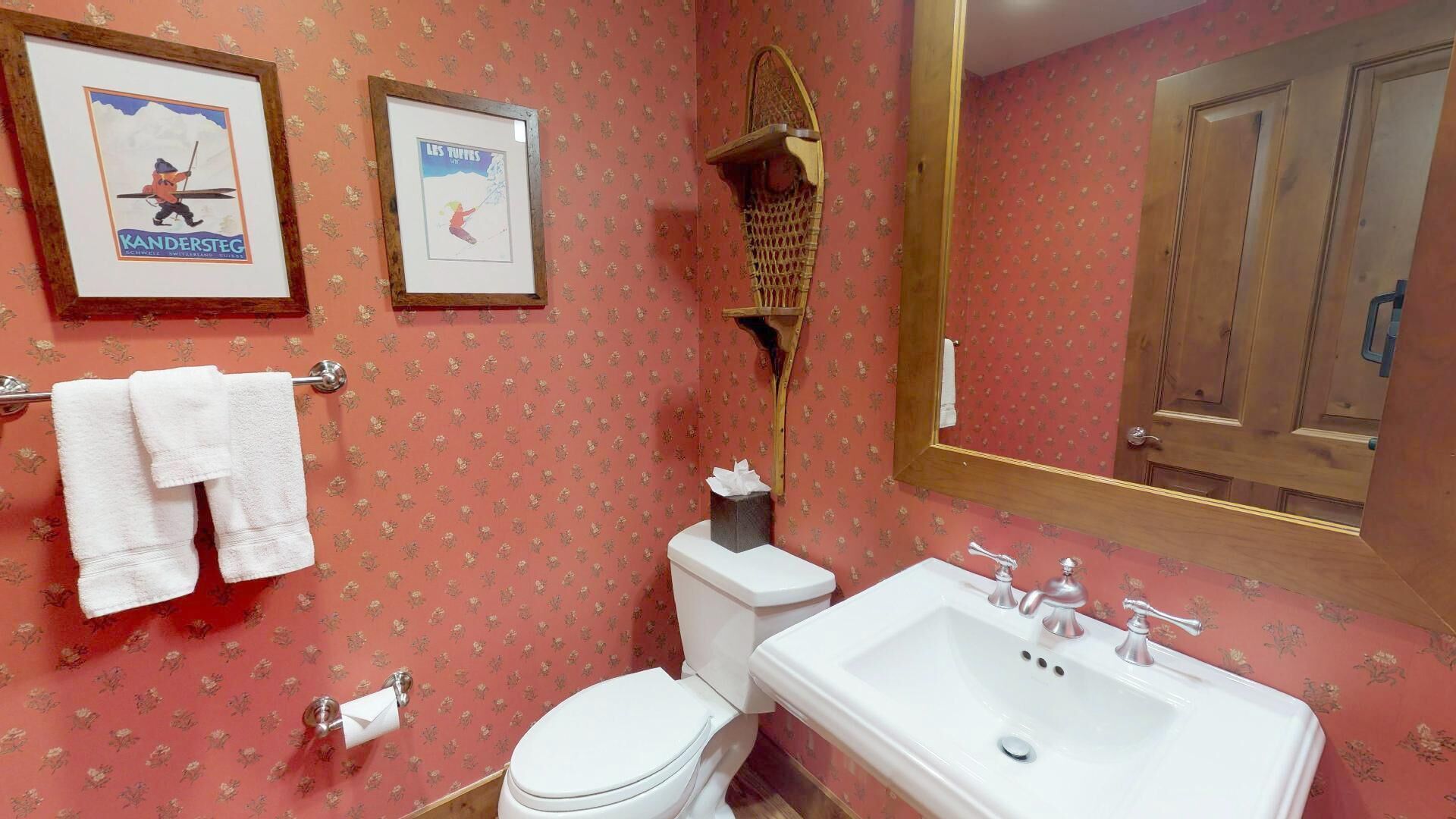 Une salle de bain équipée de toilettes, d’un lavabo et de deux tableaux encadrés accrochés au mur.