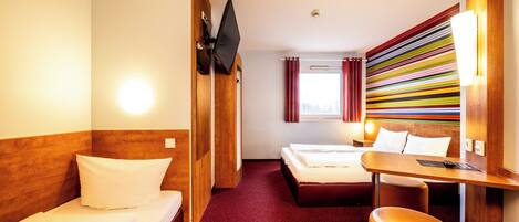A hotel room with two beds, a desk, and a small seating area.