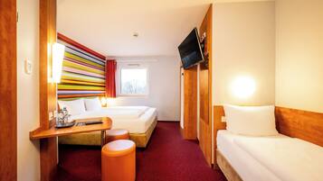 Ein Hotelzimmer mit Bett, Schreibtisch, Fernseher und Fenster.