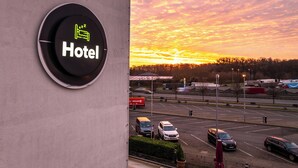 A hotel sign with a bed icon and the word "Hotel" against a sunset sky.