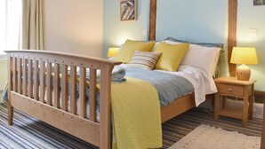 Un dormitorio con una cama de madera, una mesita de noche, una lámpara y un cuadro en la pared.