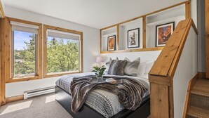 Un dormitorio con cama, ventana, radiador, planta y escalera.