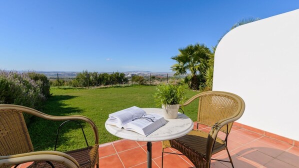 A patio with wicker chairs, a round table, and a potted plant.