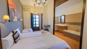 A hotel room with two beds, a bathroom with a bathtub, and a large mirror. - Cortijo Escondido Arcos de la Frontera by Ruralidays (Cádiz)