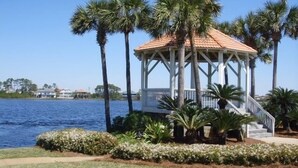 A gazebo with a tiled roof, surrounded by palm trees and a body of water. -  Luxury home with sugar white sand beach, family-friendly vacation rental house! (Destin)