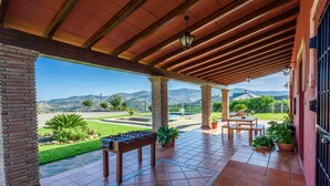 Un patio techado con mesa de fútbol, asientos exteriores y vista a las montañas.