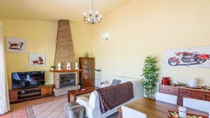 Una sala de estar con chimenea, televisor, sofá y un comedor con mesa y sillas.