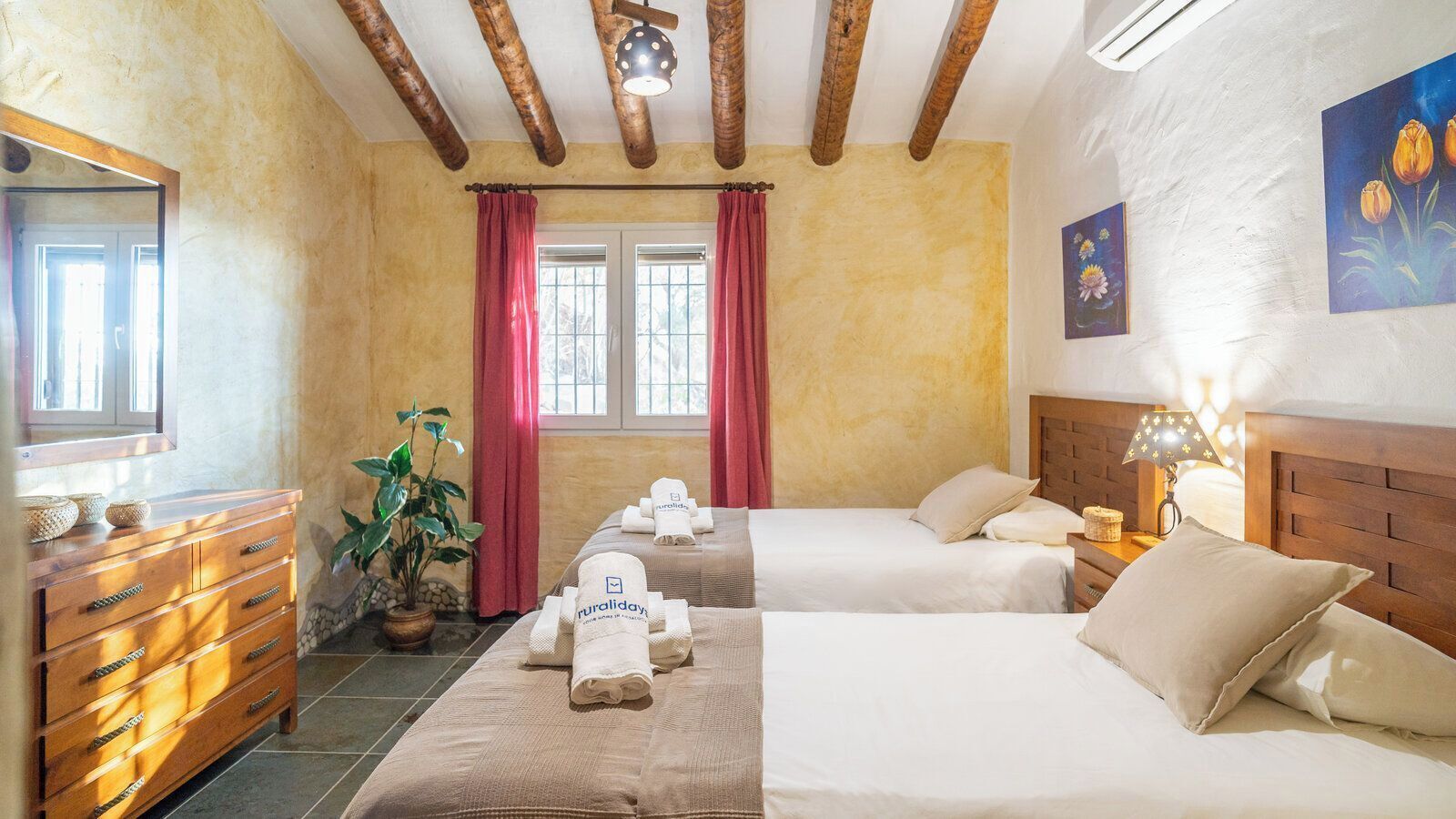 A hotel room with two beds, a wooden dresser, a potted plant, and a window with curtains.