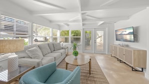 A modern living room with a sofa, armchair, coffee table, and TV.