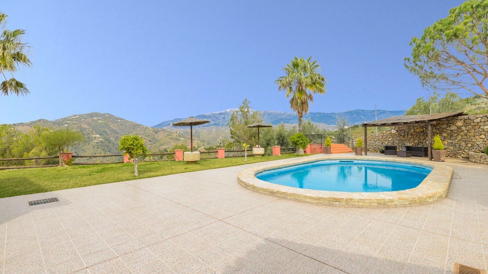 A pool area with a stone border, surrounded by potted plants and a stone wall.