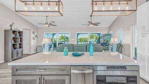 A spacious kitchen with a large island, two ceiling fans, and a view of the outdoors. - Ocean's Paradise is an exquisite 4-bedroom, 3-bathroom retreat nestled within the sought-after enclave of Sombrero Beach (Marathon)