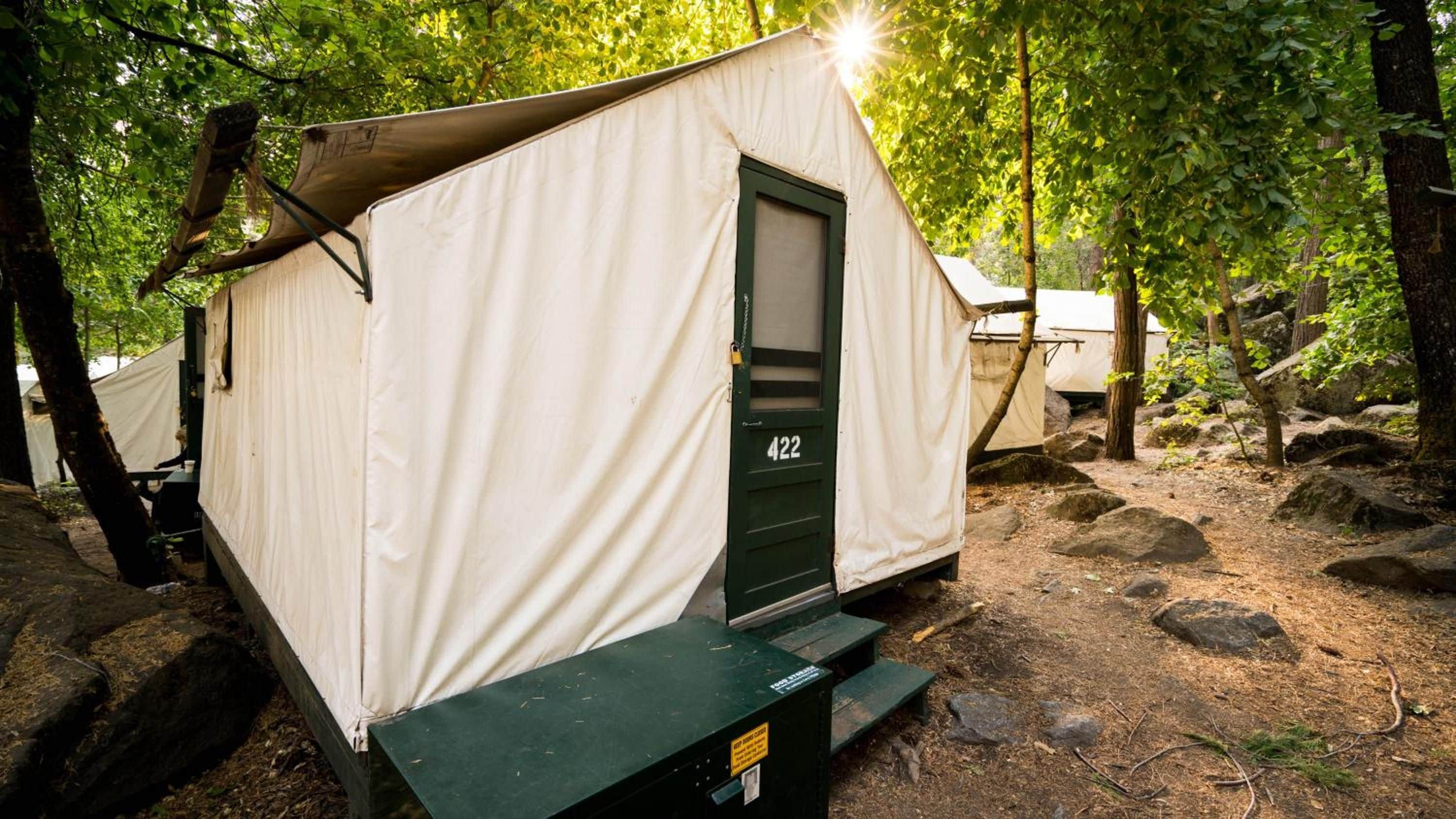 Une tente de camping portable, avec une porte marquée du numéro « 422 », située dans une zone boisée.