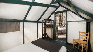 Tenda com cama, cadeira e uma pequena mesa com um aparelho.